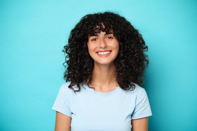 Photo of Happy young woman on light blue background. Dental veneers