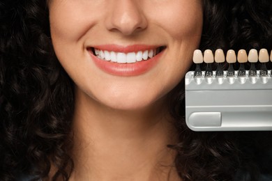 Smiling woman with teeth color samples, closeup. Dental veneers