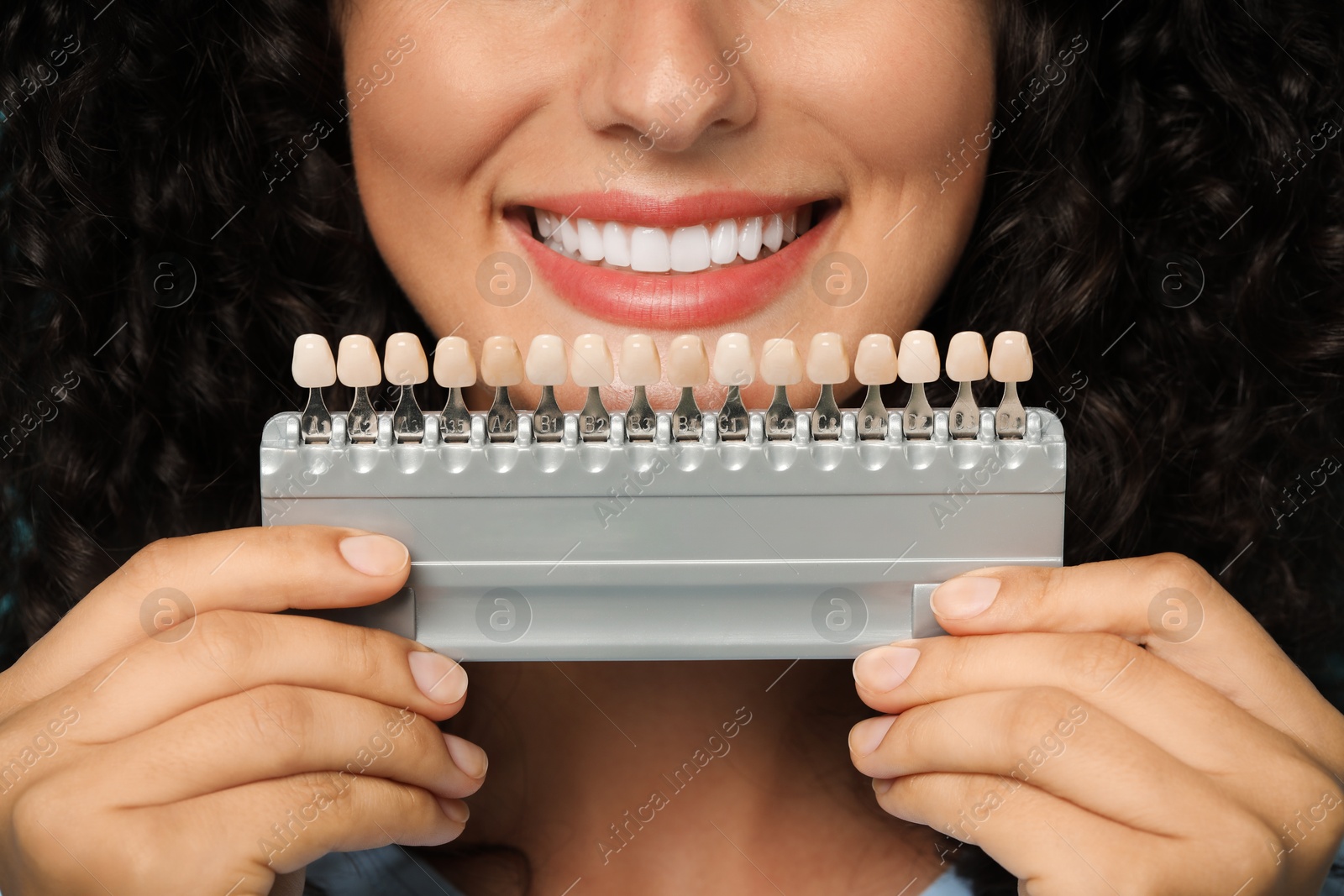 Photo of Smiling woman with teeth color samples, closeup. Dental veneers