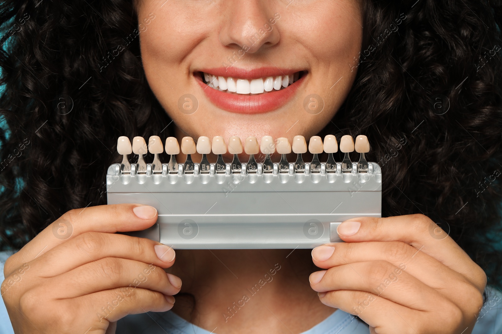 Photo of Smiling woman with teeth color samples, closeup. Dental veneers