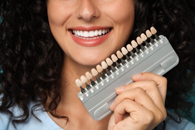 Photo of Smiling woman with teeth color samples, closeup. Dental veneers