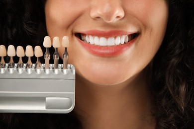 Smiling woman with teeth color samples, closeup. Dental veneers