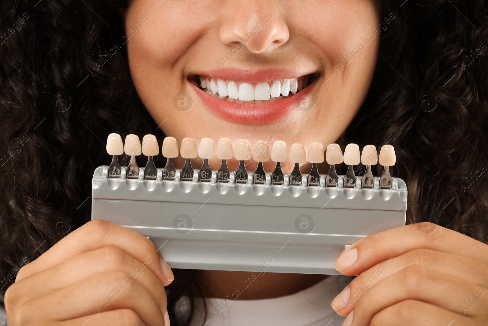 Photo of Smiling woman with teeth color samples, closeup. Dental veneers