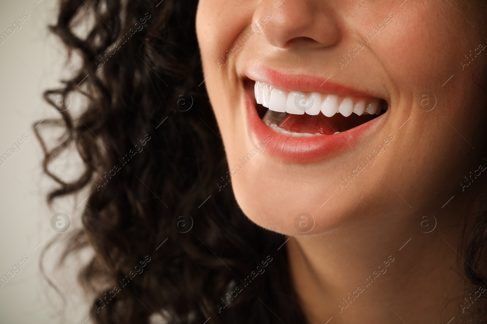 Photo of Smiling woman on light grey background, closeup. Dental veneers