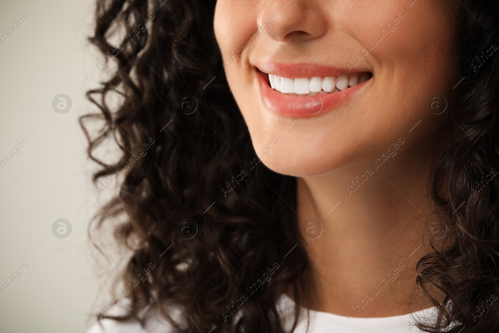 Photo of Smiling woman on light grey background, closeup. Dental veneers