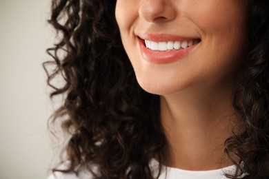 Smiling woman on light grey background, closeup. Dental veneers