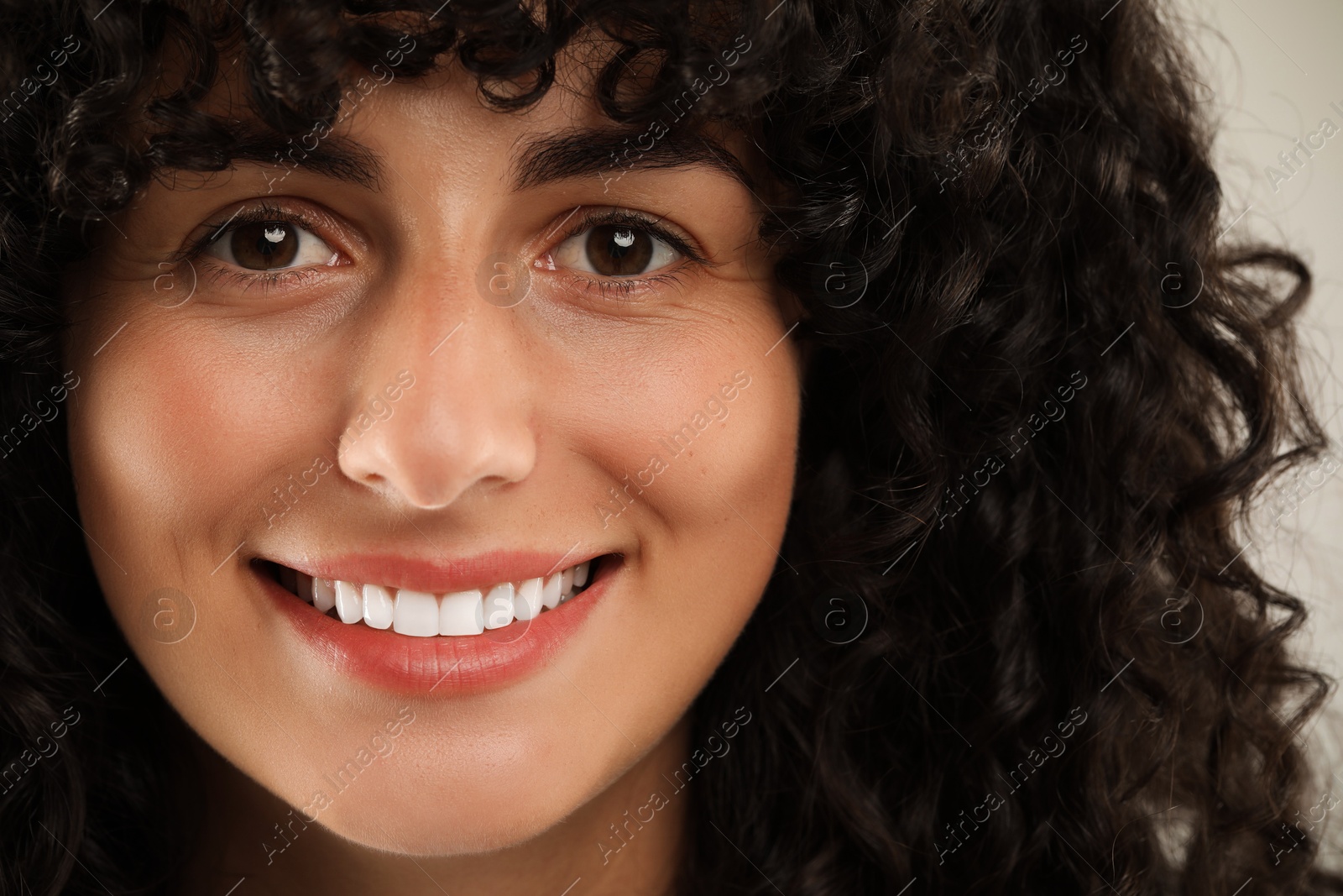 Photo of Happy young woman on light grey background, closeup. Dental veneers