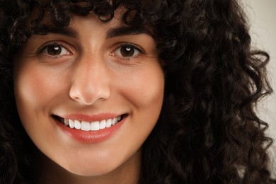 Happy young woman on light grey background, closeup. Dental veneers