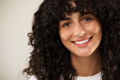 Happy young woman on light grey background, closeup. Dental veneers