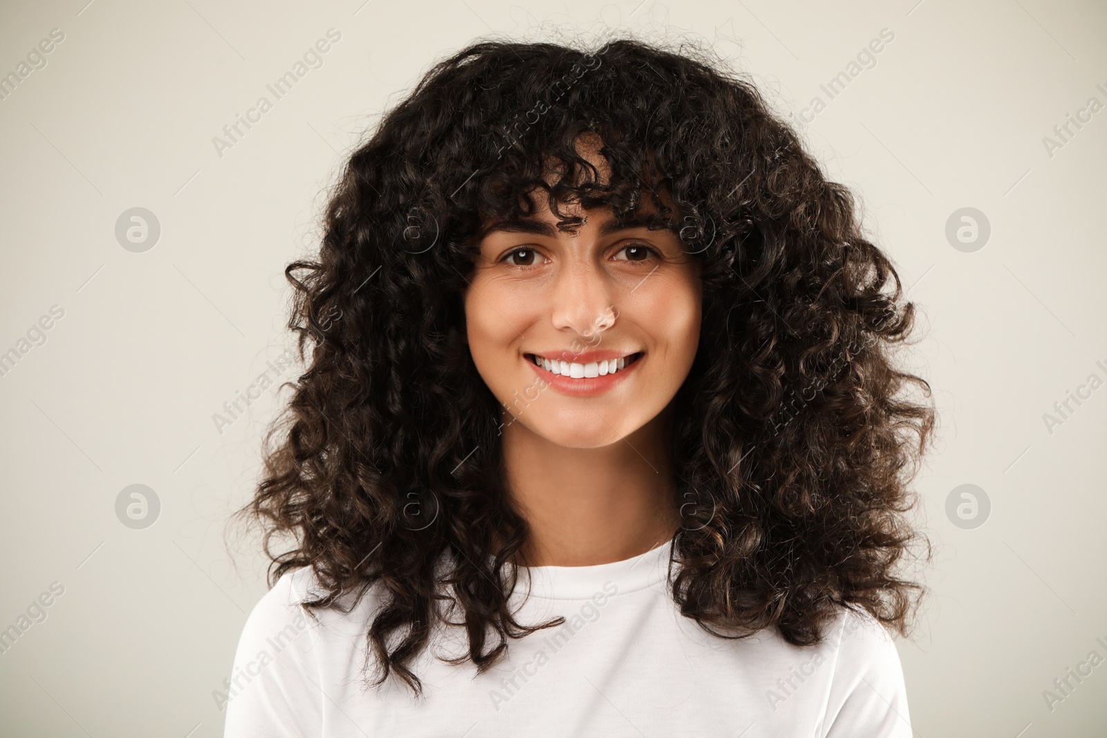 Photo of Happy young woman on light grey background. Dental veneers