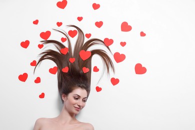 Beautiful young woman with long hair and red paper hearts on white background, top view