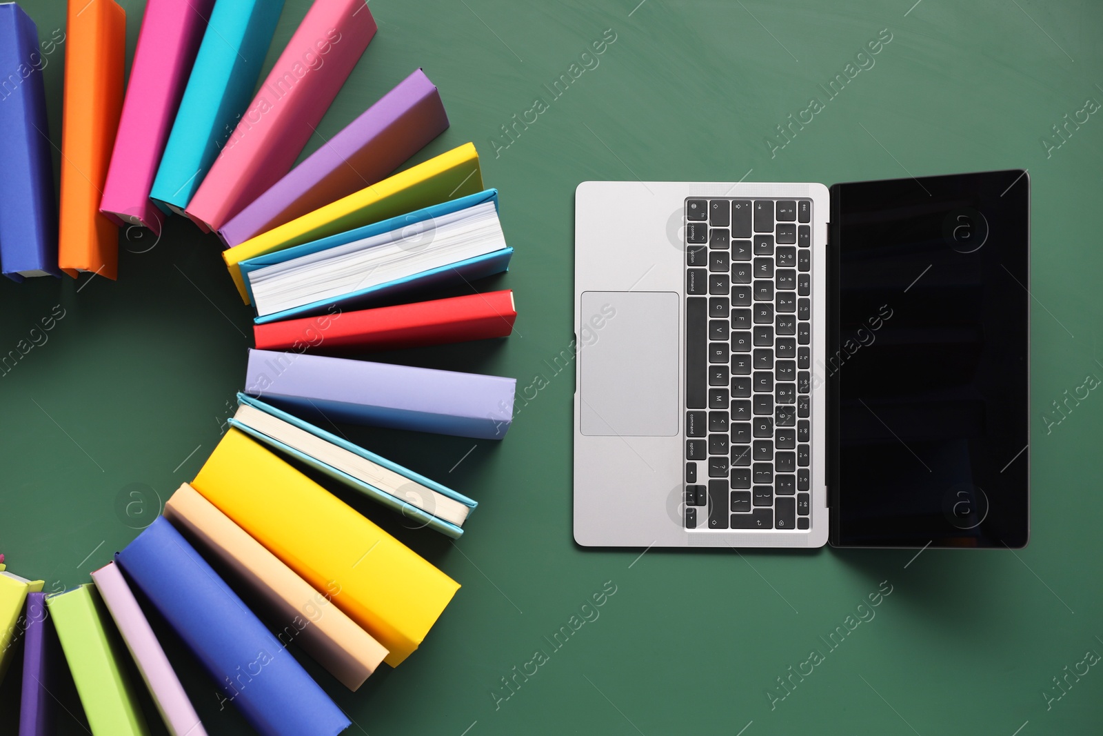 Photo of Many colorful books and laptop on green background, flat lay