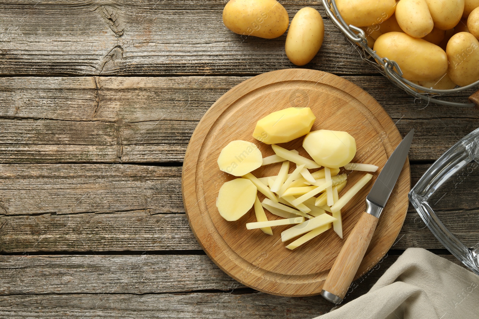 Photo of Whole and cut fresh raw potatoes near knife on wooden table, top view. Space for text