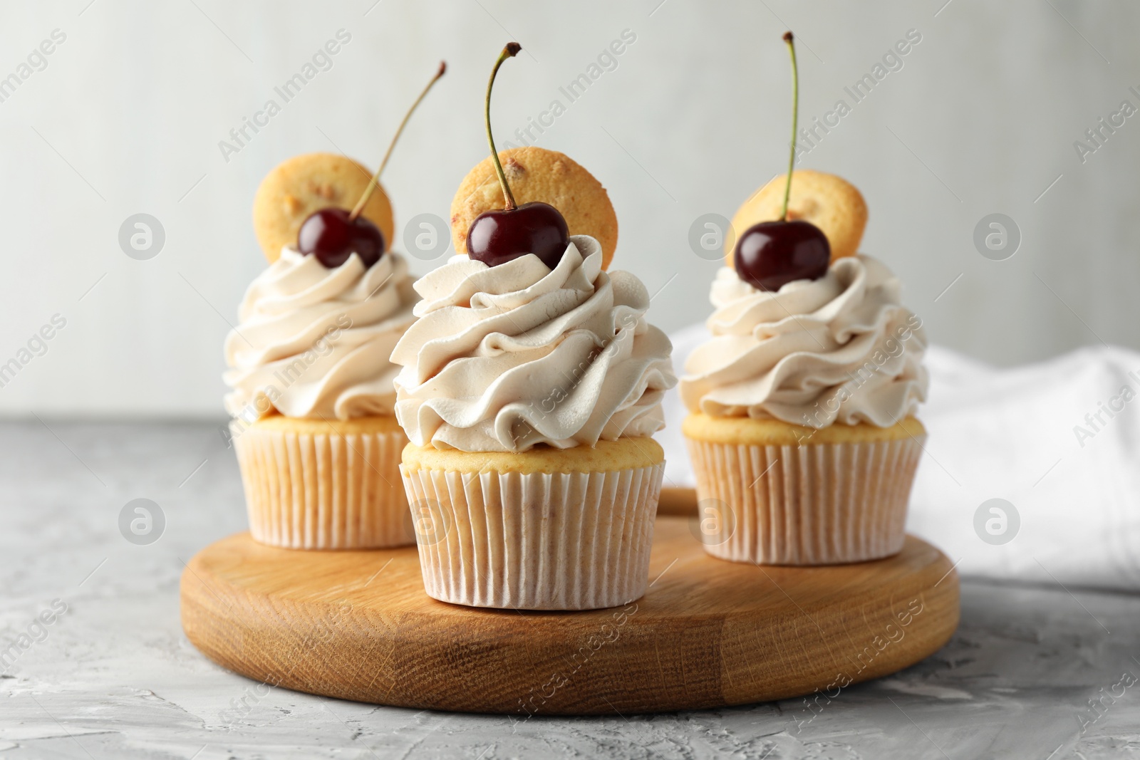 Photo of Delicious cupcakes with cherries and cookies on grey textured table, closeup