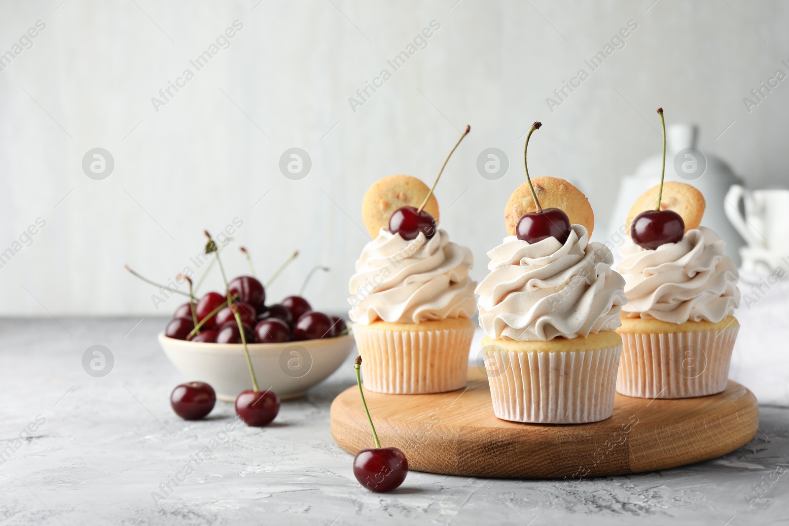 Photo of Delicious cupcakes with cherries and cookies on grey textured table