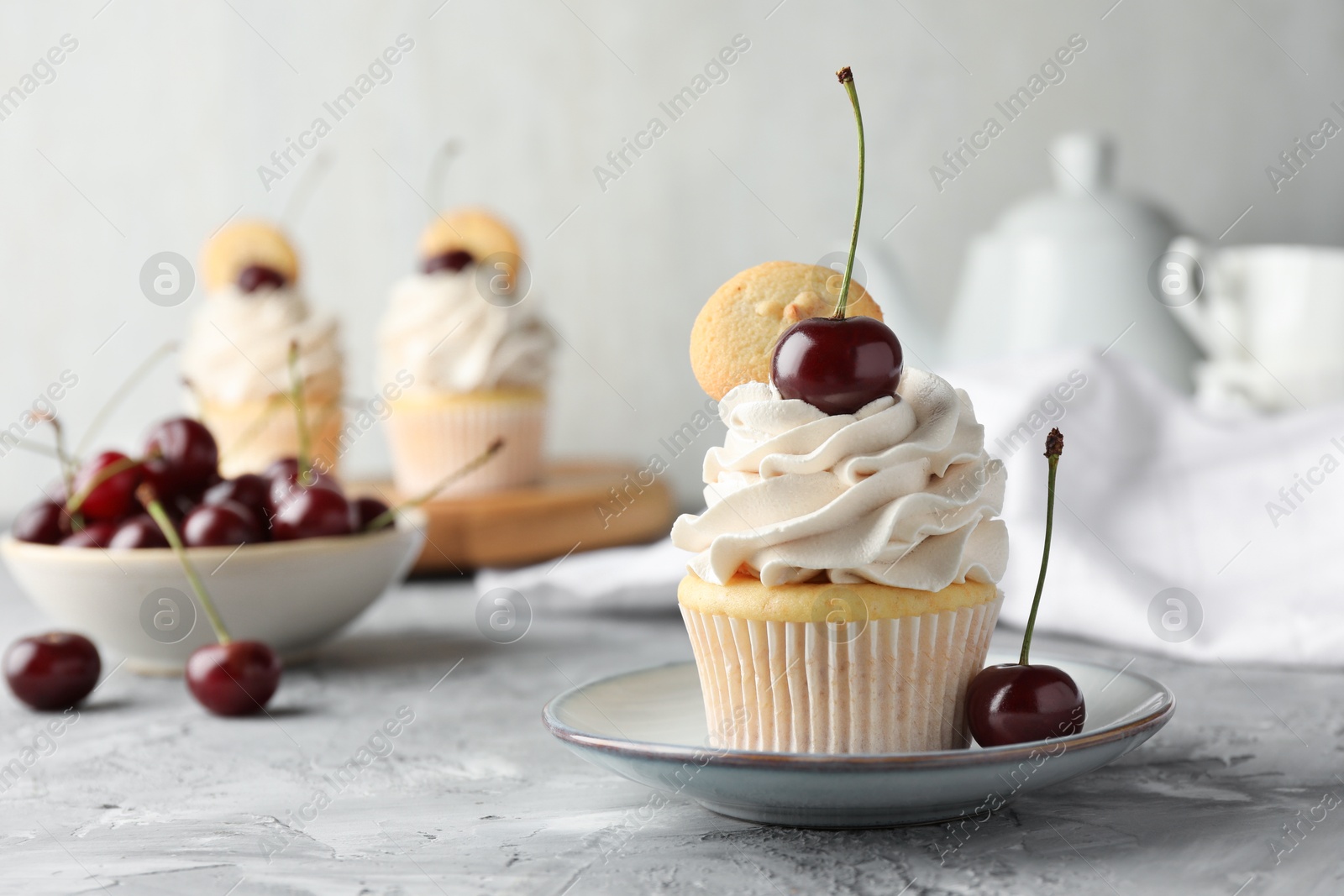 Photo of Delicious cupcake with cherries and cookies on grey textured table