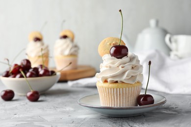 Photo of Delicious cupcake with cherries and cookies on grey textured table