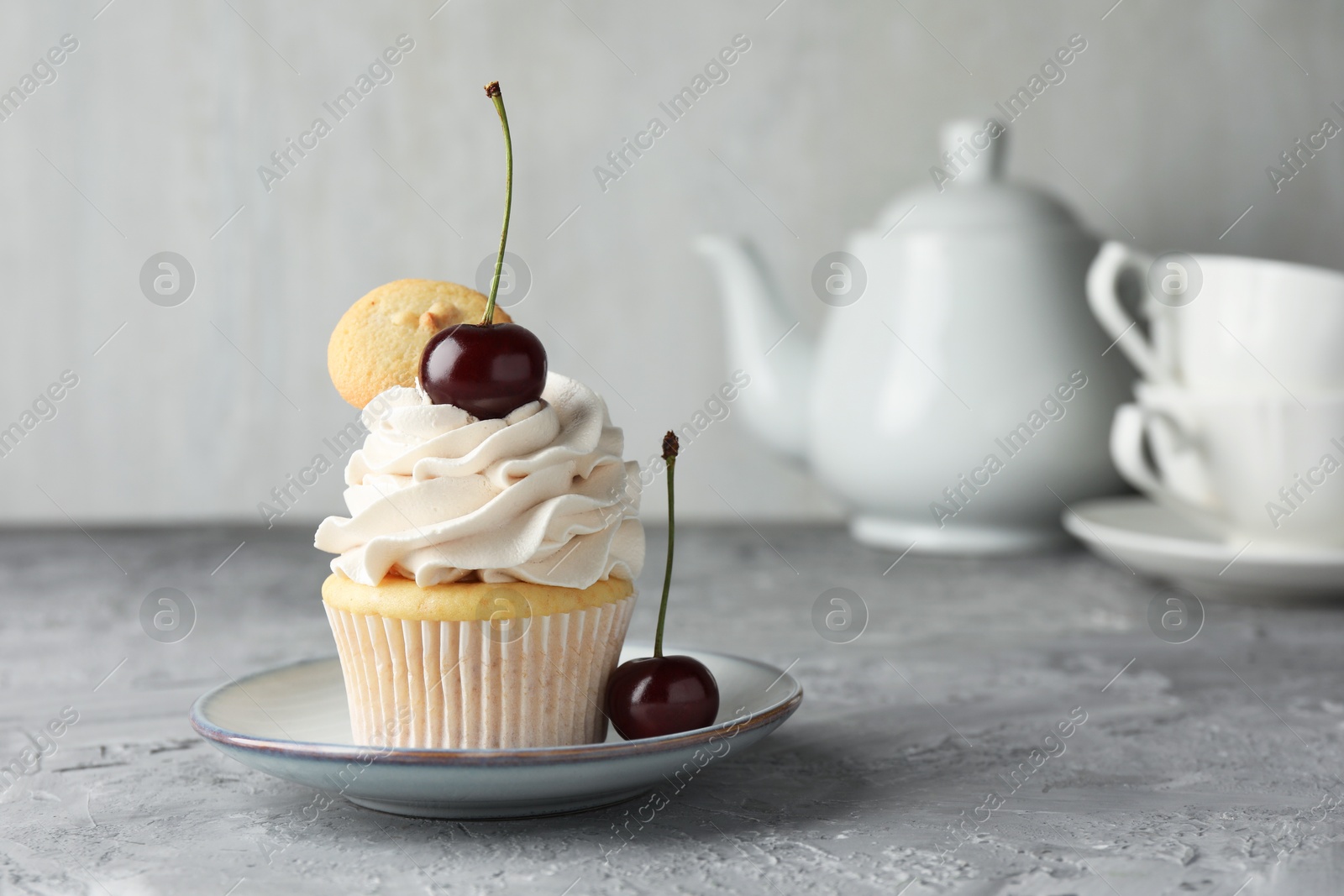 Photo of Delicious cupcake with cherries and cookie on grey textured table, closeup. Space for text