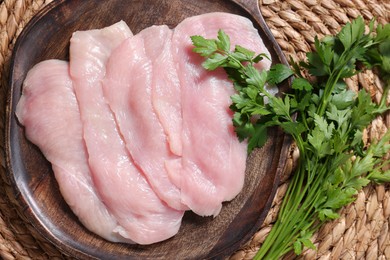 Making schnitzel. Board with raw meat and parsley on wicker mat, top view