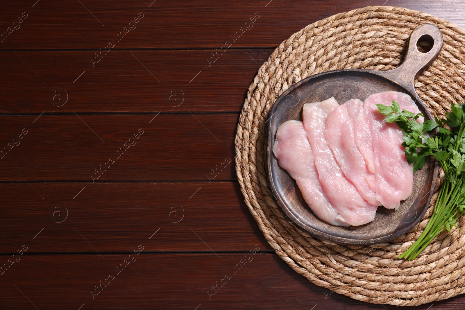 Photo of Making schnitzel. Board with raw meat and parsley on wooden table, top view. Space for text