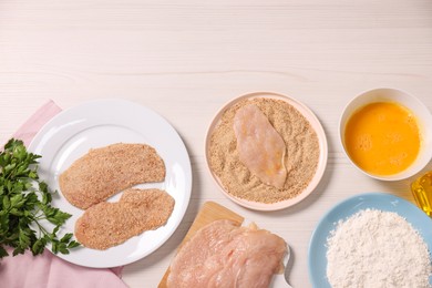 Making schnitzel. Slices of meat with bread crumbs and ingredients on white wooden table, flat lay