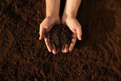 Photo of Man holding pile of soil outdoors, top view