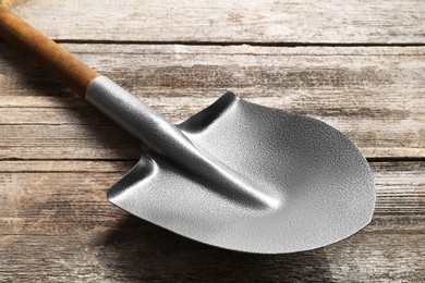 Photo of Metal shovel with handle on wooden table, closeup