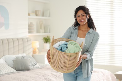 Happy woman with basket full of laundry in bedroom