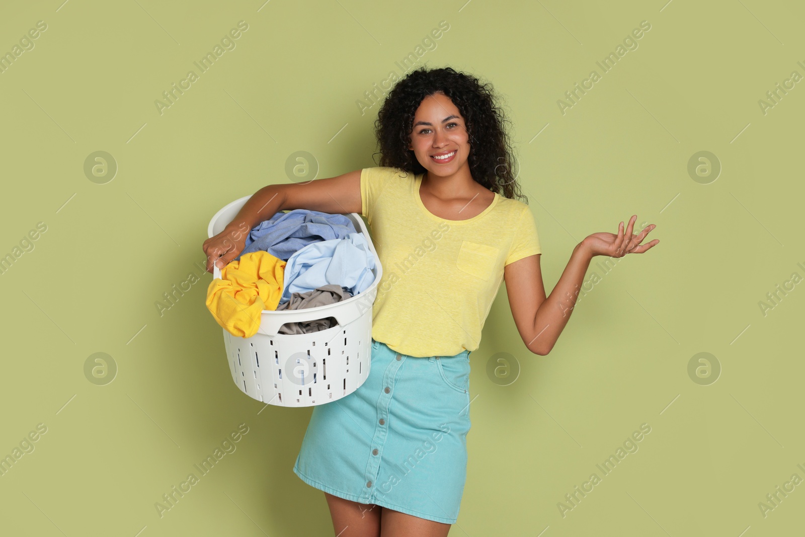 Photo of Happy woman with basket full of laundry on olive background