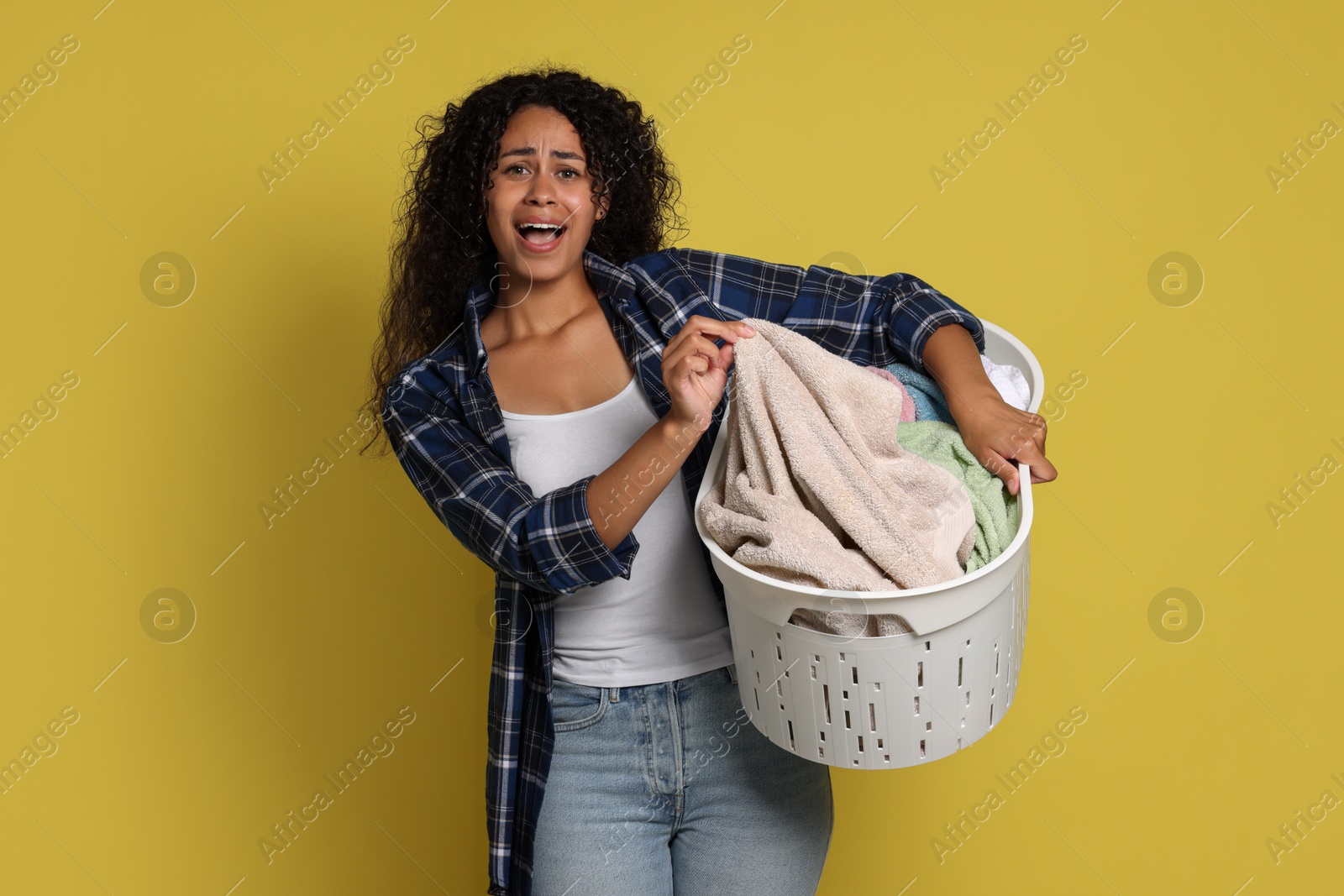 Photo of Emotional woman with basket full of laundry on yellow background