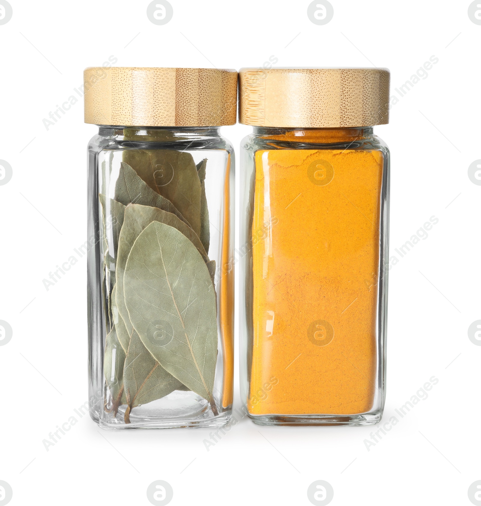 Photo of Bay leaves and curry powder in glass jars isolated on white