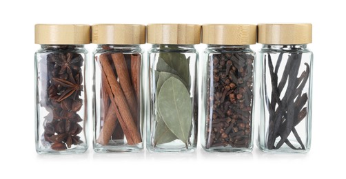 Photo of Different spices in glass jars isolated on white