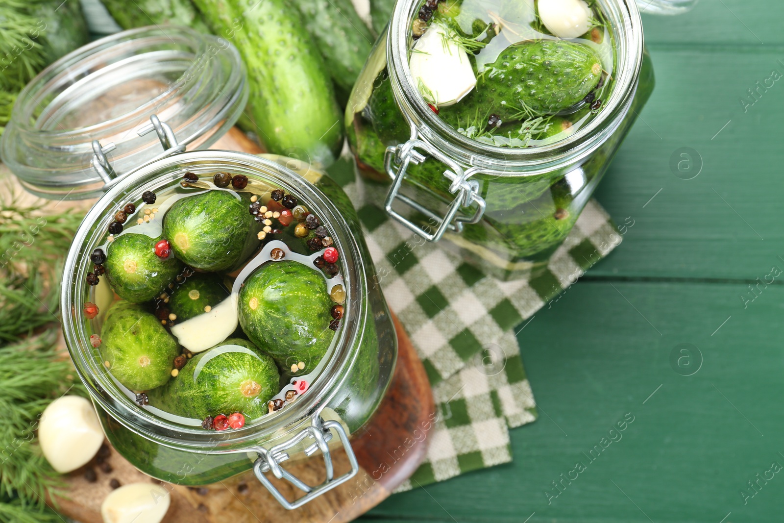 Photo of Making pickles. Fresh cucumbers and spices in jars on wooden table, flat lay