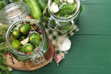 Photo of Making pickles. Fresh cucumbers and spices in jars on wooden table, flat lay