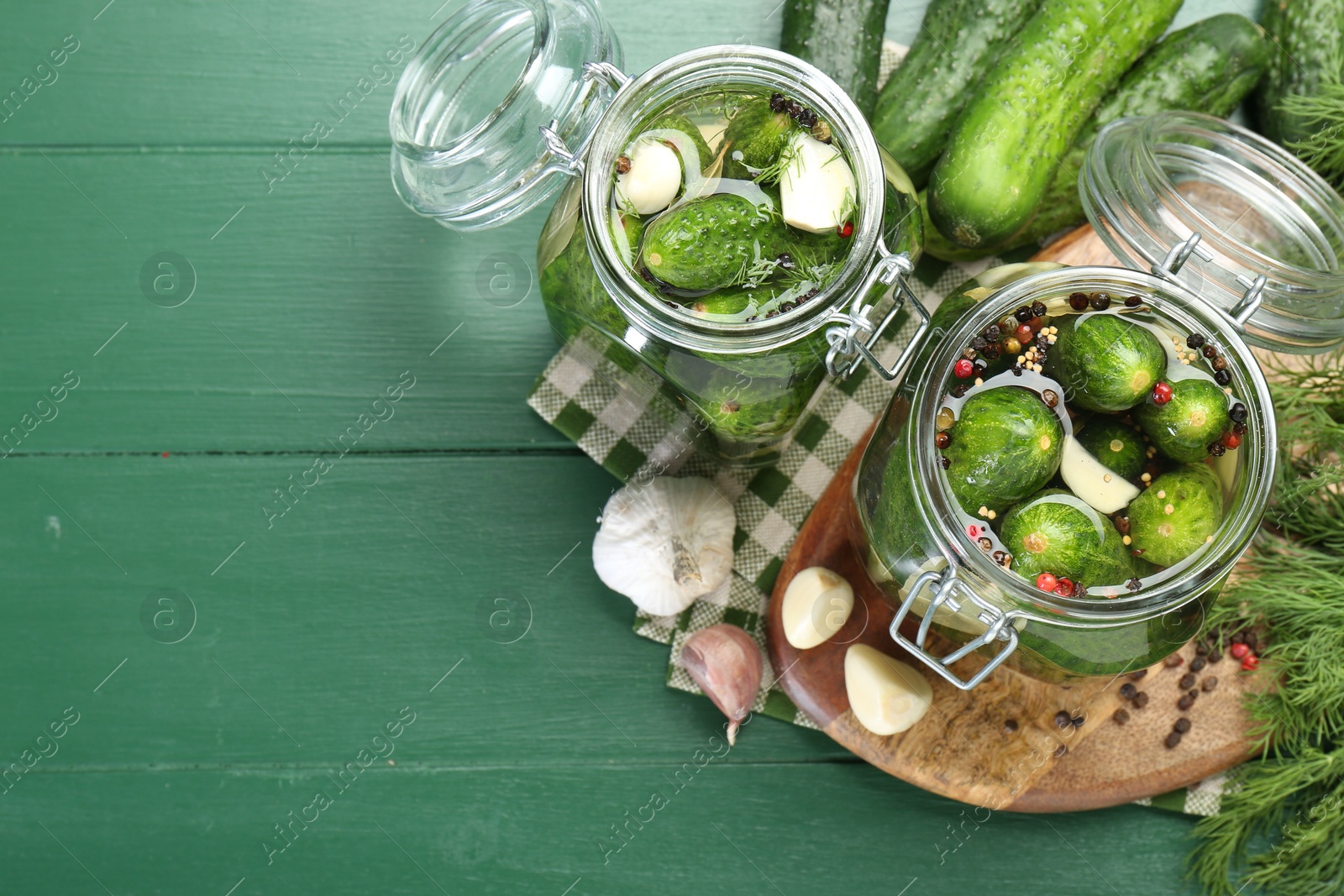 Photo of Making pickles. Fresh cucumbers and spices in jars on wooden table, flat lay. Space for text