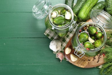 Photo of Making pickles. Fresh cucumbers and spices in jars on wooden table, flat lay. Space for text