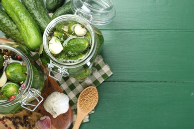 Photo of Making pickles. Fresh cucumbers and spices in jars on wooden table, flat lay. Space for text