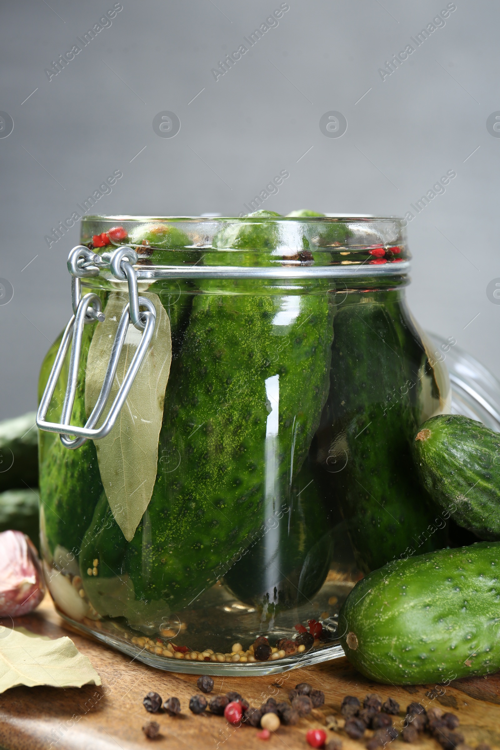 Photo of Making pickles. Fresh cucumbers and spices in jar on wooden table, closeup