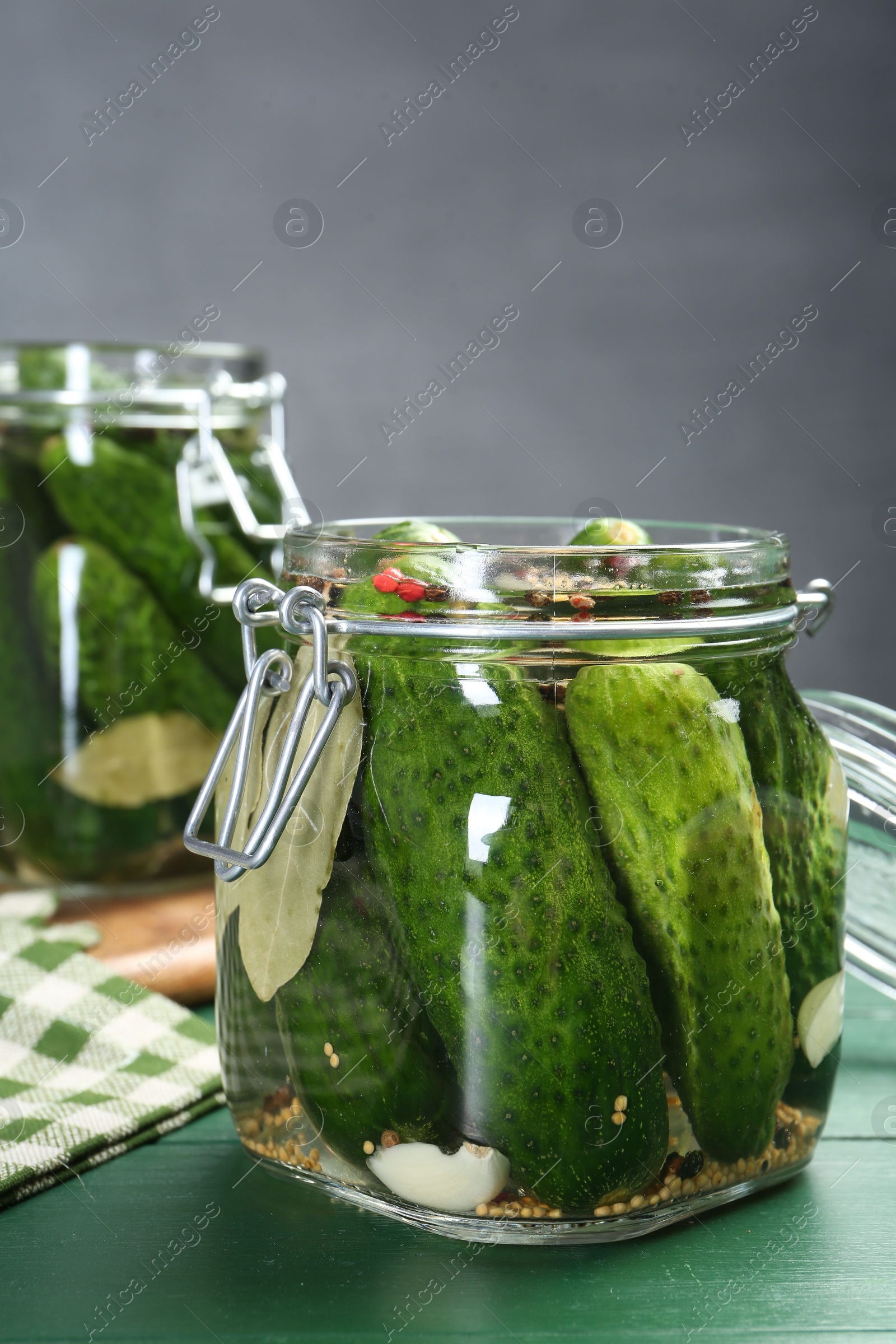 Photo of Making pickles. Fresh cucumbers and spices in jars on wooden table