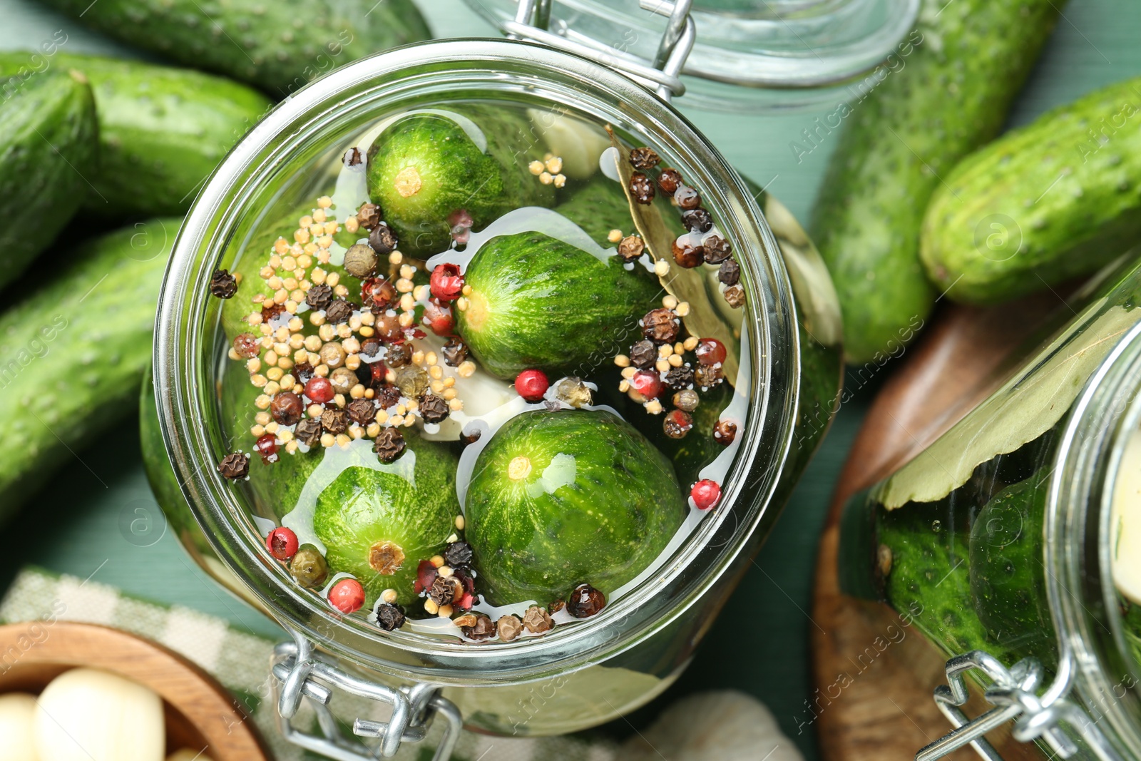 Photo of Making pickles. Fresh cucumbers and spices in jar on wooden table, flat lay