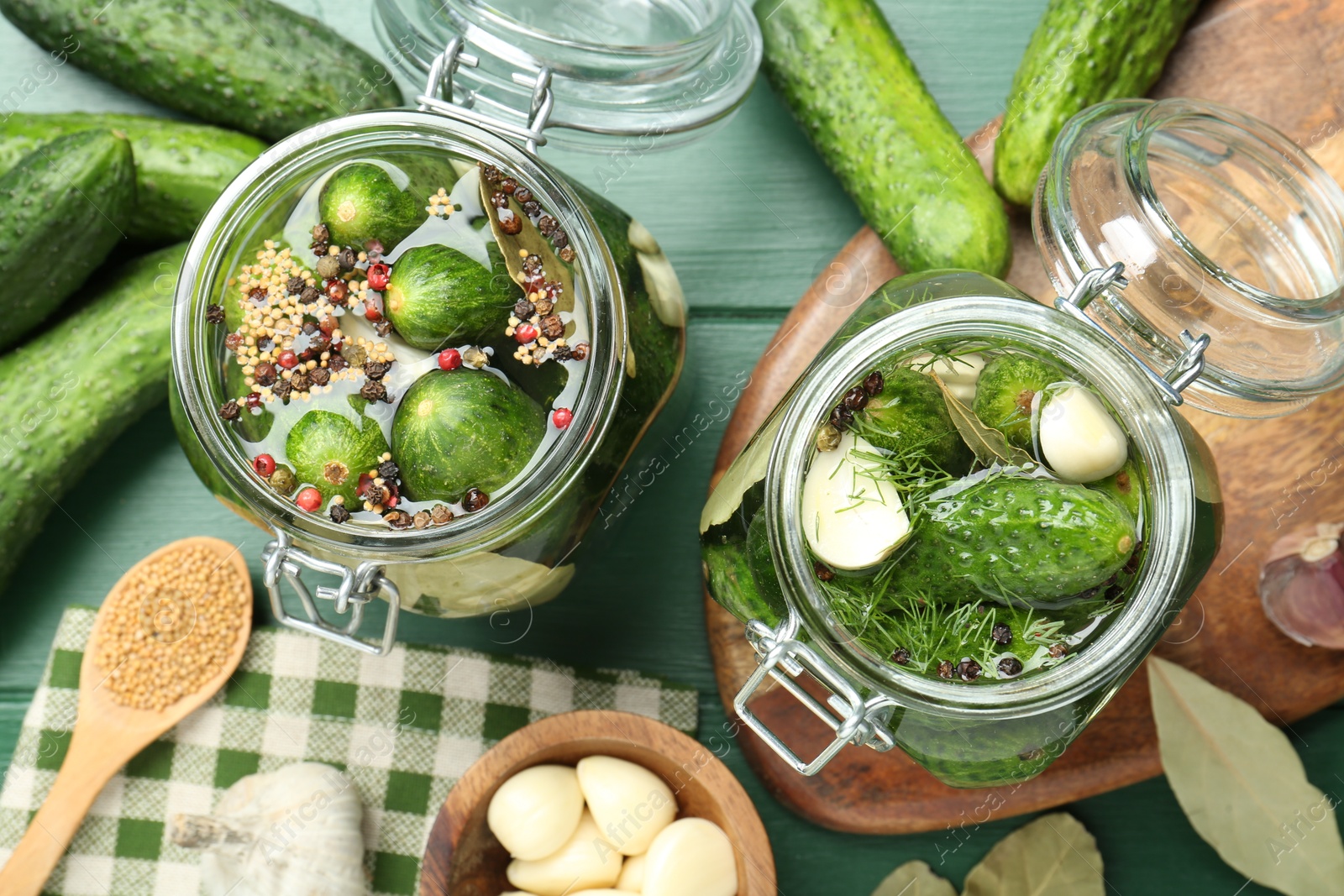 Photo of Making pickles. Fresh cucumbers and spices in jars on wooden table, flat lay