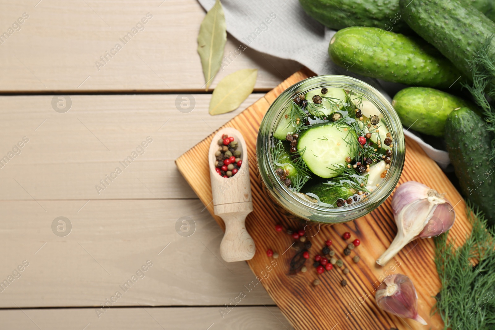 Photo of Making pickles. Fresh cucumbers and spices in jar on wooden table, top view. Space for text