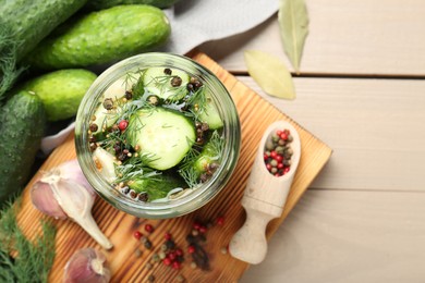 Photo of Making pickles. Fresh cucumbers and spices in jar on wooden table, top view