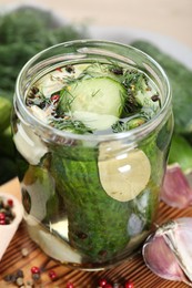 Photo of Making pickles. Fresh cucumbers and spices in jar on wooden table, closeup