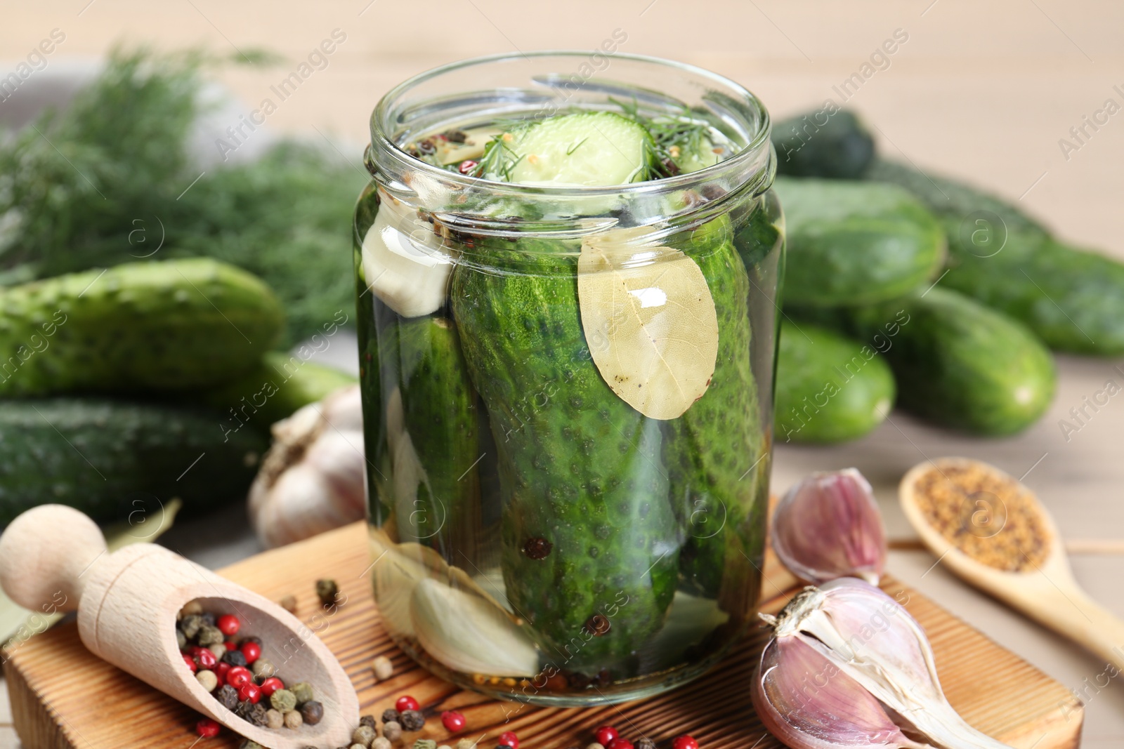 Photo of Making pickles. Fresh cucumbers and spices in jar on wooden table, closeup