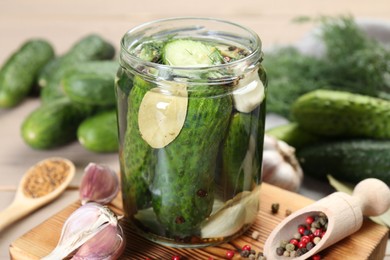 Photo of Making pickles. Fresh cucumbers and spices in jar on wooden table, closeup