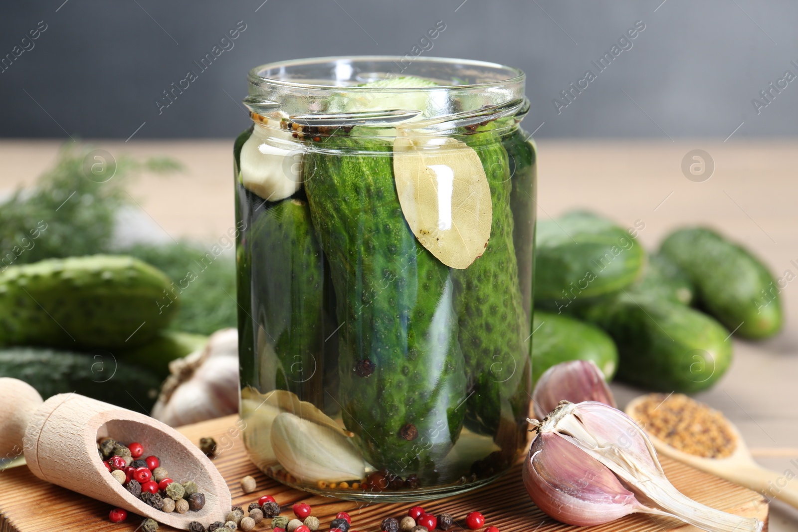 Photo of Making pickles. Fresh cucumbers and spices in jar on wooden table, closeup