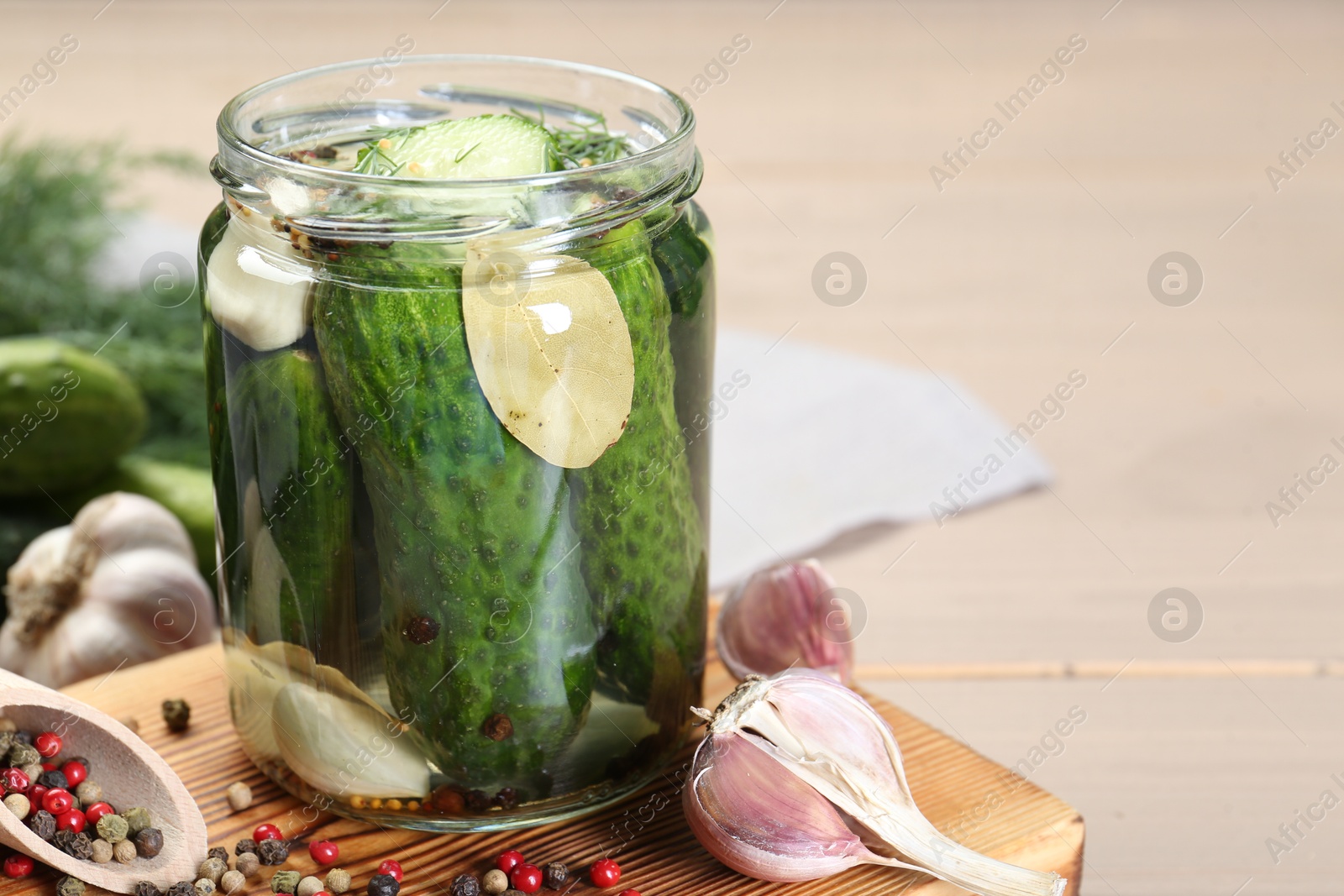 Photo of Making pickles. Fresh cucumbers and spices in jar on wooden table, closeup. Space for text