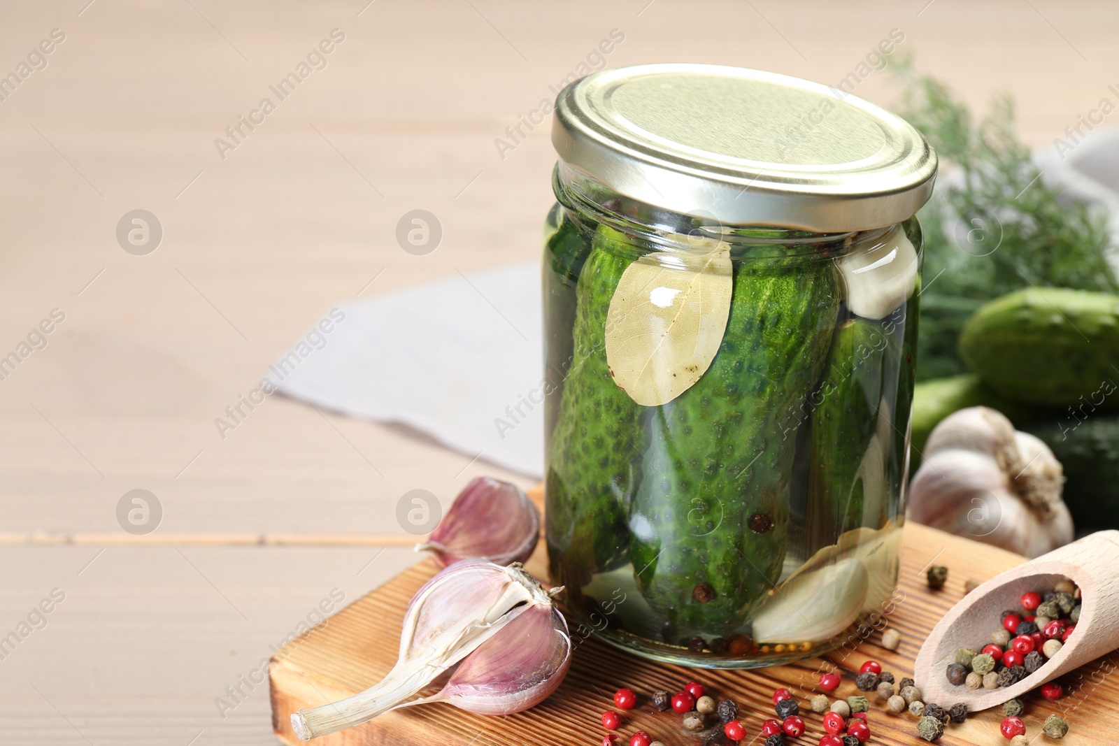 Photo of Making pickles. Fresh cucumbers and spices in jar on wooden table, closeup. Space for text