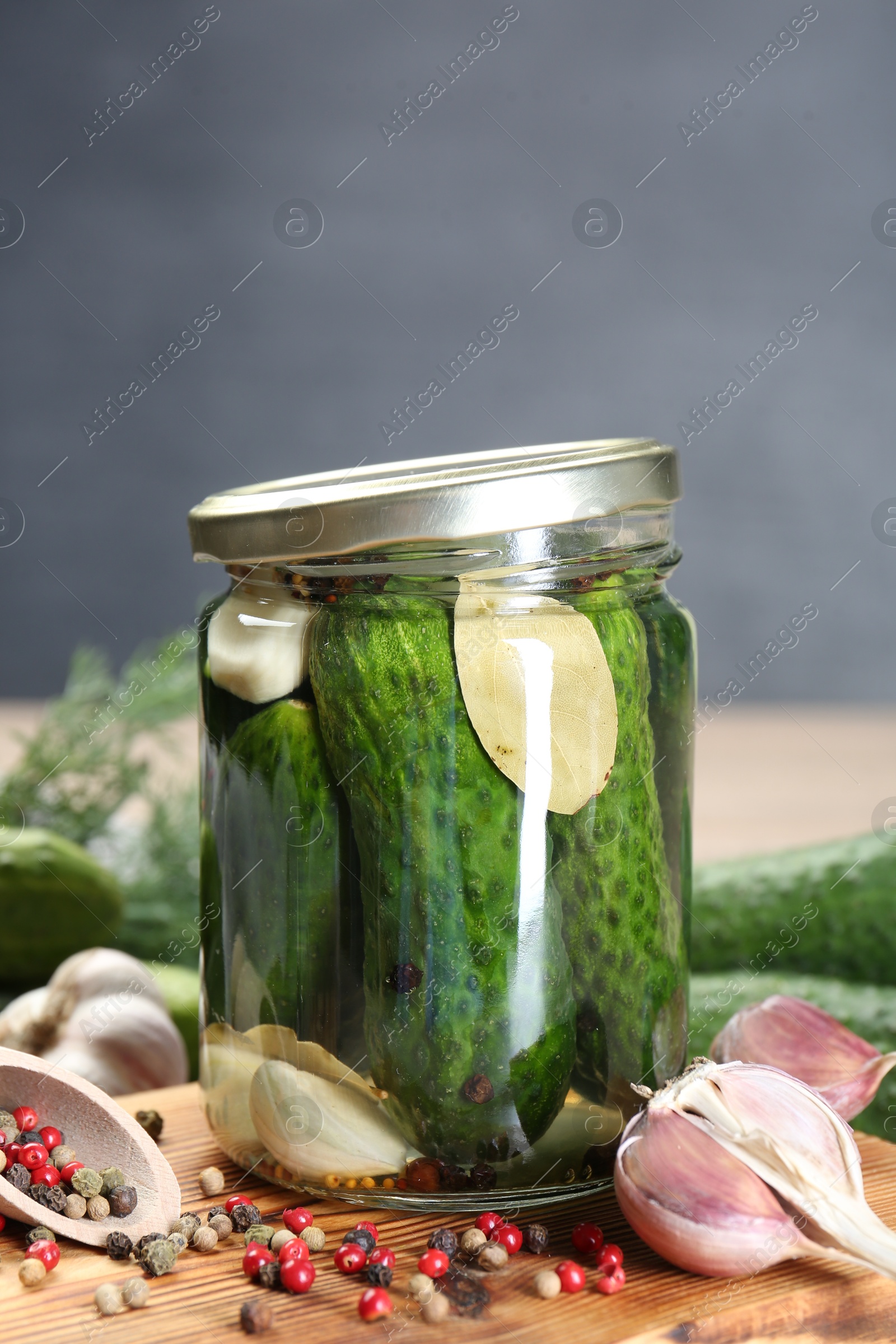 Photo of Making pickles. Fresh cucumbers and spices in jar on wooden table